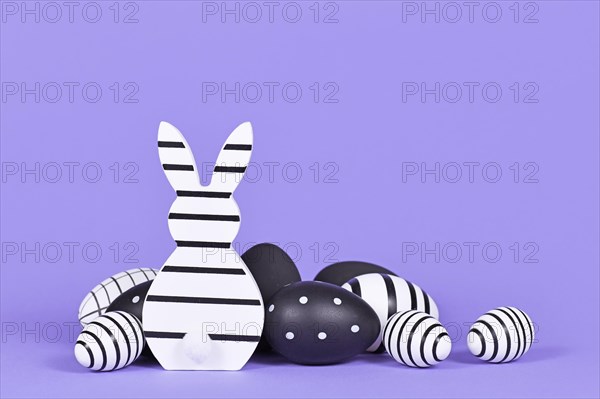 Modern black and white easter bunny ornament and eggs on violet background