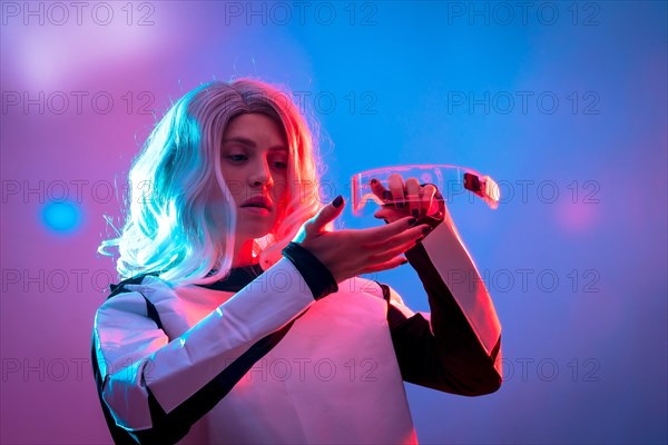 Beautiful woman adjusting futuristic glasses on a dark background