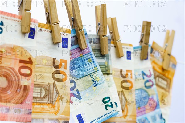 Euro banknotes hung on a clothesline with clothespins white background for copy space