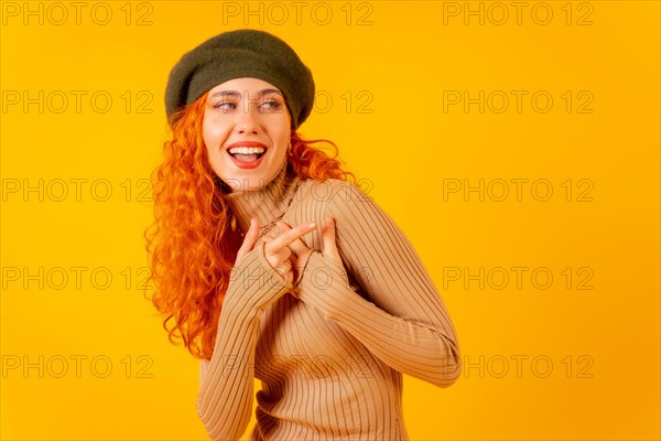 Red-haired woman in beret in studio on a yellow background