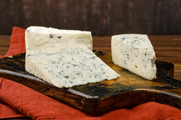 Three types of blue cheese on shabby wooden serving board
