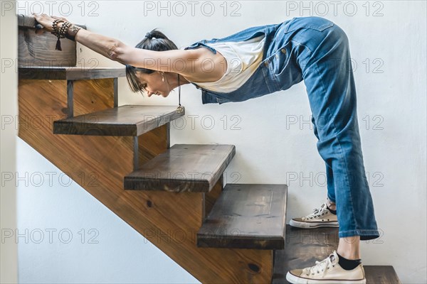 A woman doing stretching exercises on the stairs of her home. Wellbeing concept