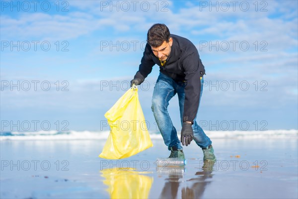 Volunteer man collecting garbage or plastic on the beach. Ecology concept