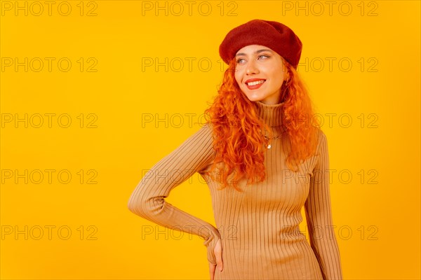 Portrait of red-haired woman in a red beret on a yellow background