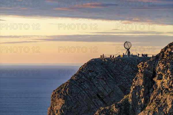 Rock cliff of the North Cape with steel globe at midnight sun
