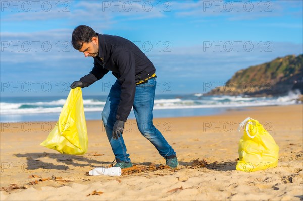 Volunteer person collecting plastic from the sand on the beach. Ecology concept