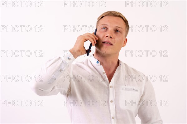 Caucasian blond businessman man making a work call with the phone on a white background