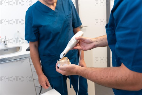 A doctor in the dental clinic explaining to a female doctor how to scan a denture