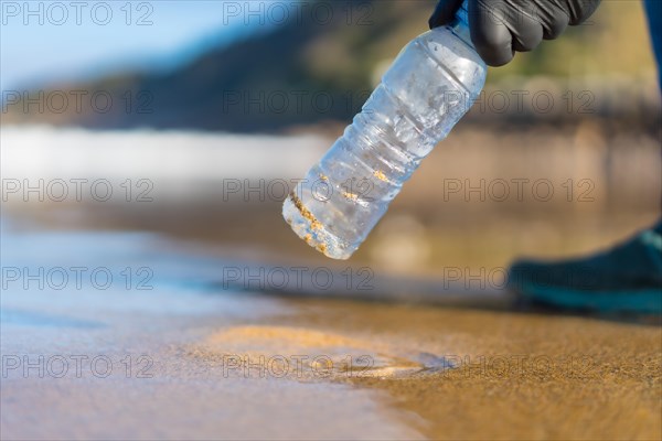 Hand of unrecognizable person picking up garbage or plastic on the beach. ecology concept