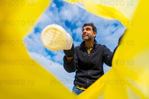 Volunteer throwing a plastic bottle into a garbage bag on the beach. Ecology