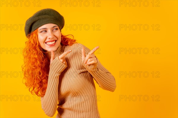 Red-haired woman in beret in studio on a yellow background