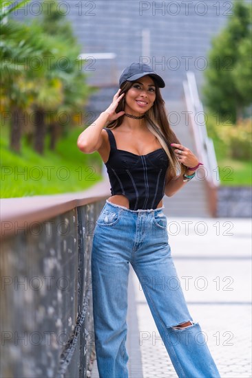 Portrait of a young brunette woman in a black cap and jeans in the city