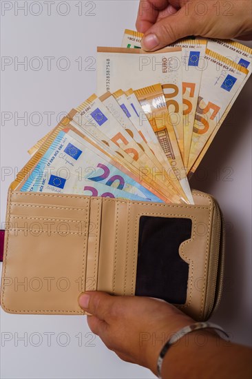 Woman's hands taking euro banknotes out of her wallet with white background and copy space