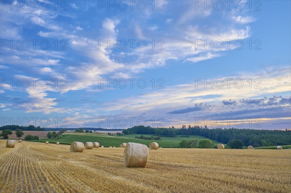 Landscape with hay field and straw bales at sunset