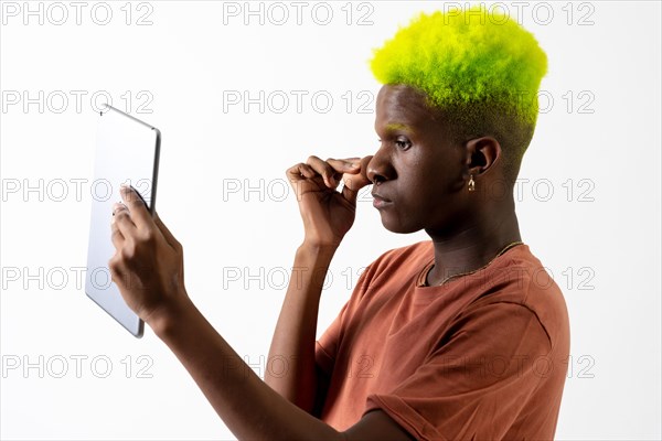 A gay black ethnic man putting on makeup