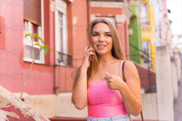 Young blonde caucasian tourist in a street with houses with colorful facades