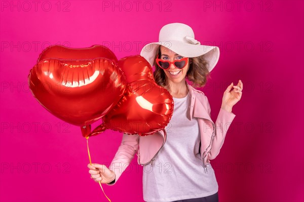 Portrait of a caucasian woman having fun dancing with a white hat in a nightclub with some heart balloons