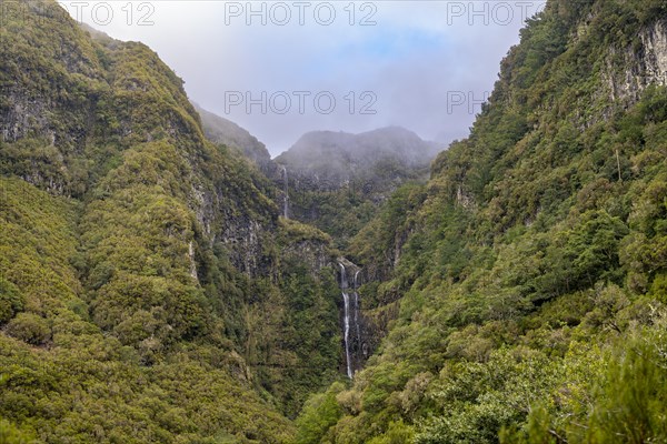 Cascata do Risco waterfall between densely forested mountains