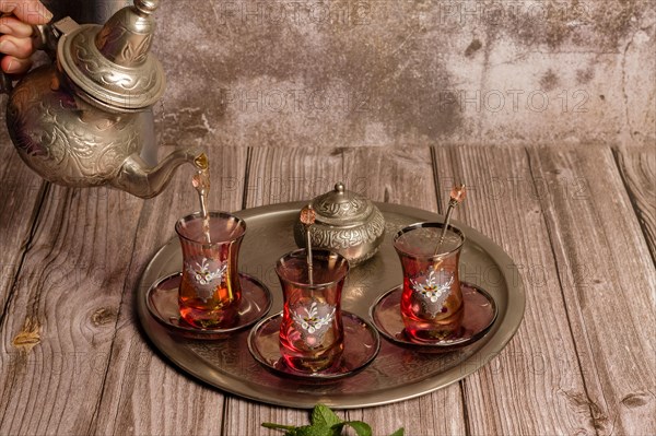 Serving hot Moorish tea on a tray with glasses and pitcher on a wooden table