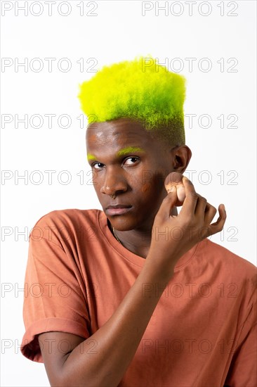 An androgynous black man posing putting on makeup