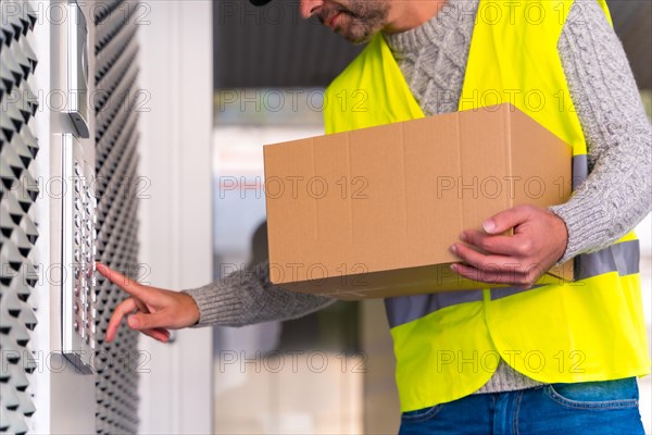 A young delivery man in a protective uniform at the delivery of the online order in a home