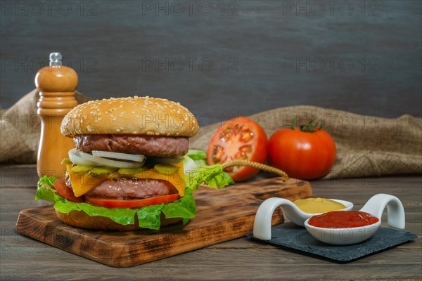 Close-up of a delicious whole hamburger on a wooden board and sauces