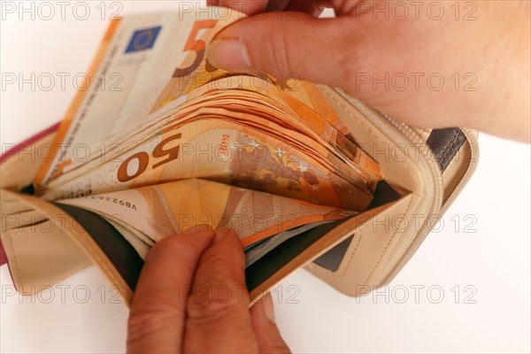 Woman's hands taking euro banknotes out of her wallet with white background and copy space
