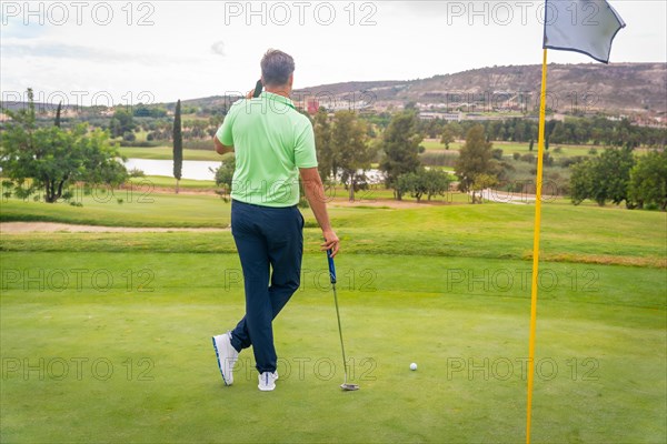 Young businessman playing golf and answering a work call with the phone