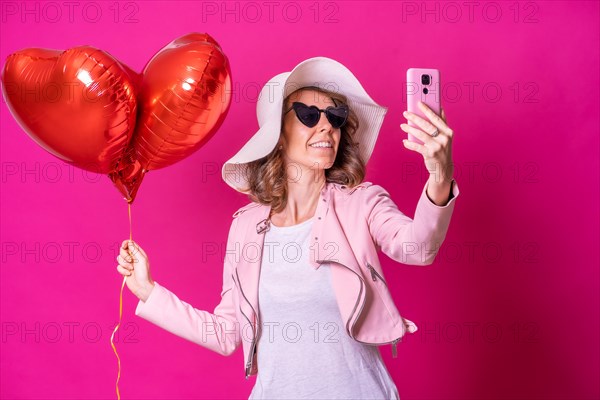 A caucasian woman having fun with a white hat in a nightclub with some heart balloons