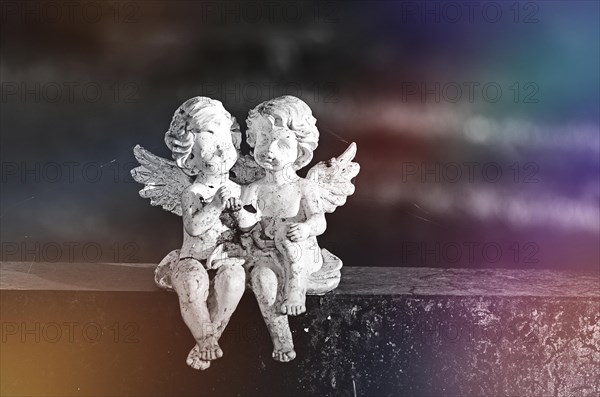 Two angel figures sitting on a gravestone