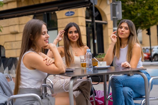 Portrait of young female friends having a drink one afternoon on a cafeteria terrace