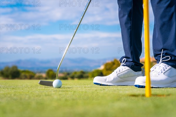Putting the ball into the hole on the green with the putter. man playing golf
