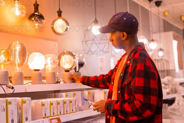 Black ethnic man shopping in a supermarket for lamps