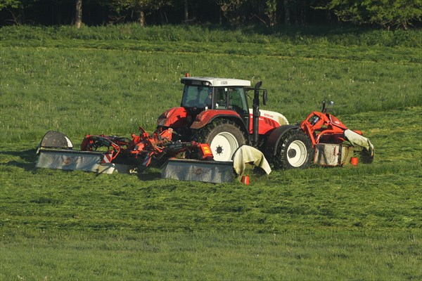 Tractor with three mowers cuts high grass