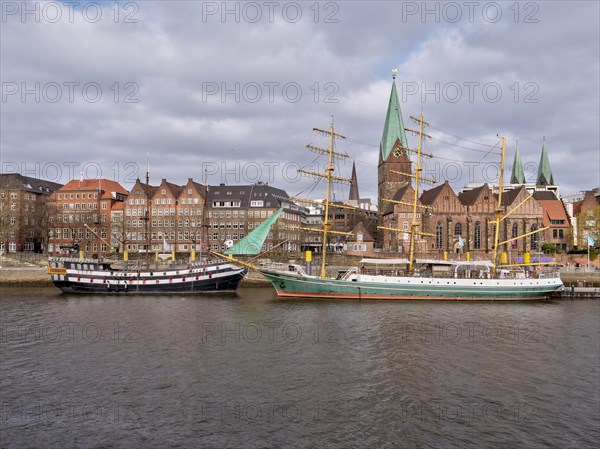 A faithful replica of the frigate "Picton Sea Eagle" and the sailing ship "Alexander von Humboldt" on the banks of the Weser with the red brick buildings of the old town in the background