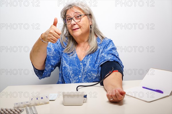 Woman taking her blood pressure with a nod of approval everything ok