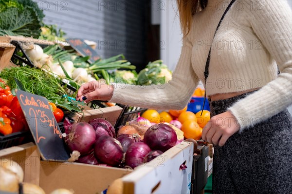 Woman buying vegetables and greens in grocery store