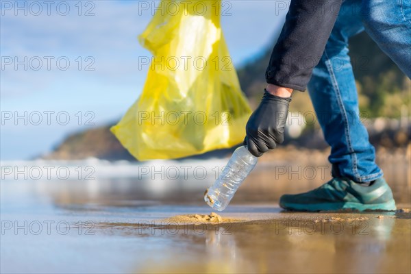 Unrecognizable person collecting garbage or plastic on the beach. ecology concept