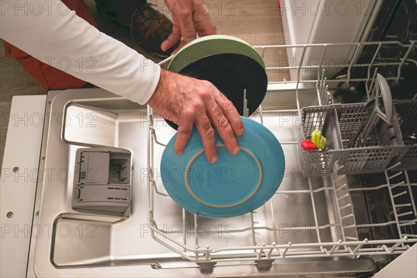 Man in white t-shirt putting the dishes in the dishwasher