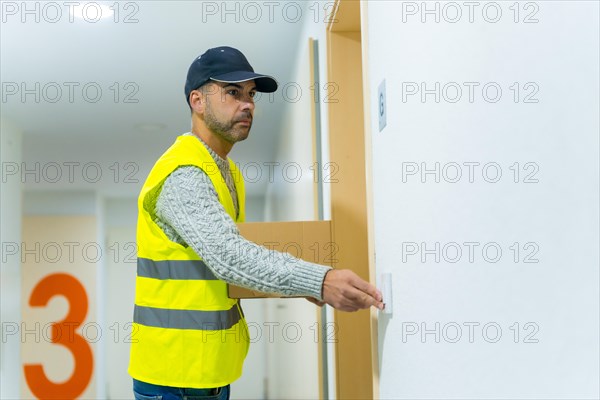 A young delivery man in a protective uniform at the delivery of the online order