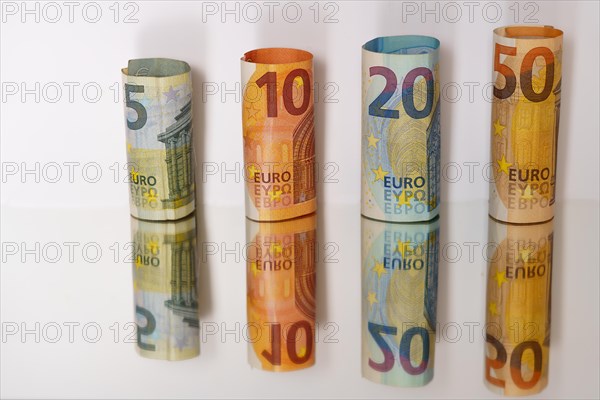 Rolled euro banknotes reflected in a mirror with copy space