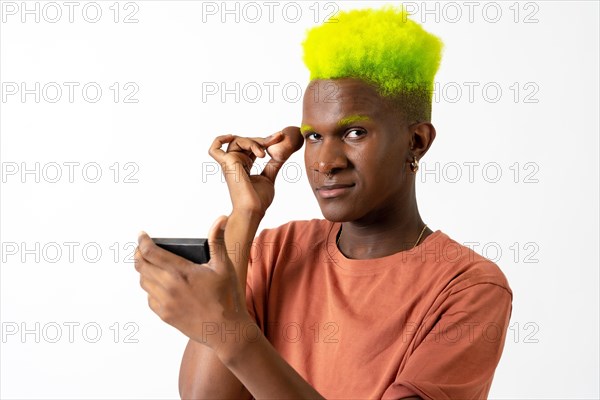 An androgynous black man posing putting on makeup