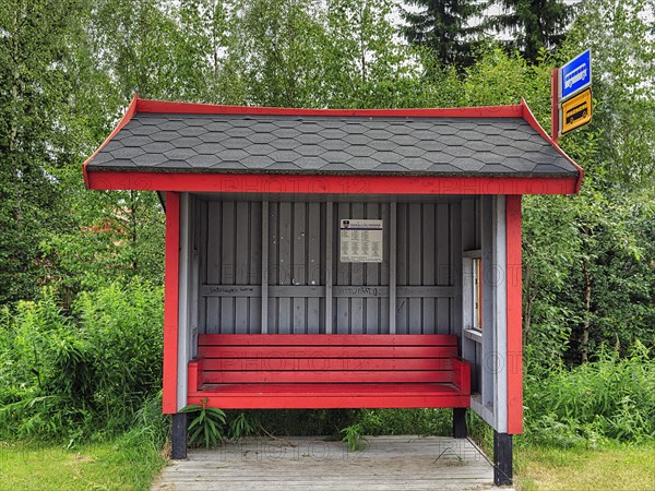 Bus shelter with red wooden bench