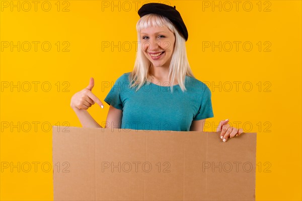 Smiling and pointing at empty cardboard advertisement poster