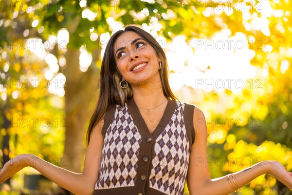 Portrait of a brunette model in autumn at sunset in a natural park smiling