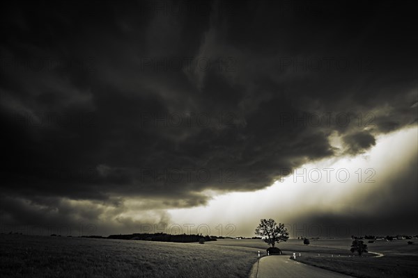 Road and meadows with thunderstorm sky in the background