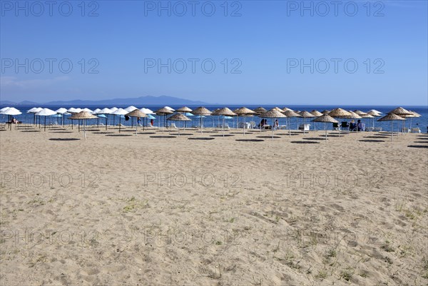 Straw parasols on the sandy beach on the Aegean Sea