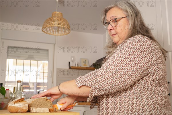 White-haired woman cutting slices of freshly baked homemade bread
