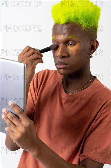 A gay black man putting on makeup