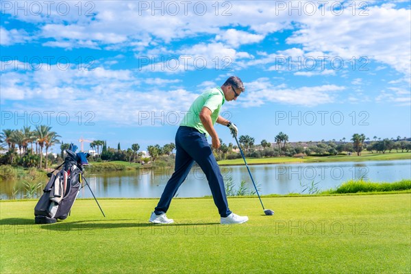 Male golf player on professional golf course. Golfer with golf driver stick preparing the shot